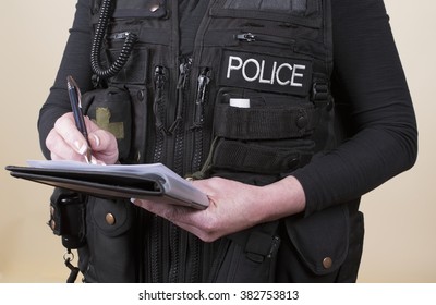 Police officer wearing tactical vest writing notes on a pad - Powered by Shutterstock