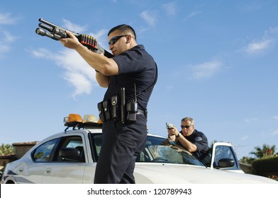 Police Officers Aiming With Gun By Car