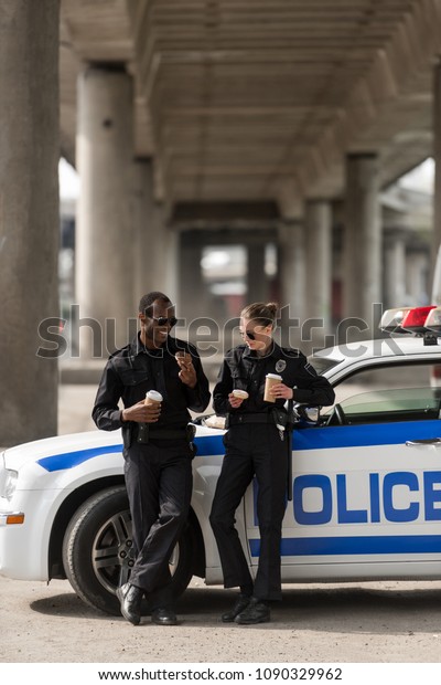 police officers with coffee and doughnuts standing\
next to car