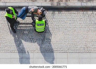 Police officers during patrol next to homeless man lying on the bench in the city