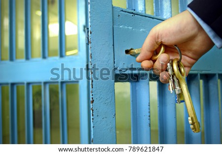 Police officers locks the door in prison corridor.