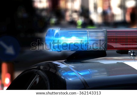 Police patrol car with flashing lights and siren on during the night raid against crime