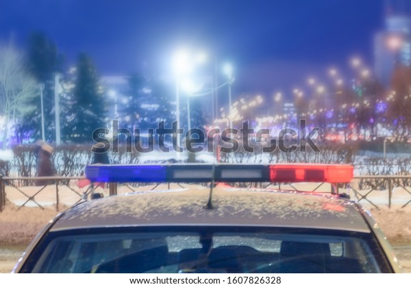 Police patrol car with flashing lights on a night city\
street,soft focus 