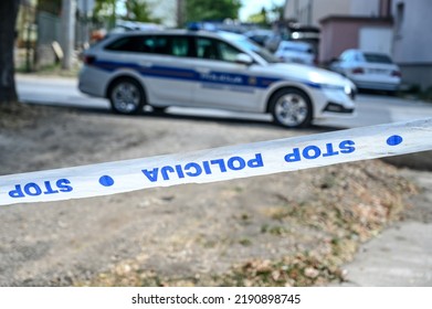 Police patrol car and police tape marking off a crime scene on a street. Barricade tape lettering: Stop, police
