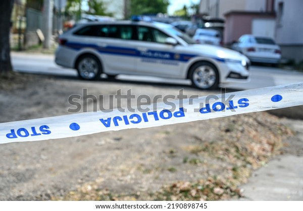 Police patrol\
car and police tape marking off a crime scene on a street.\
Barricade tape lettering: Stop,\
police\