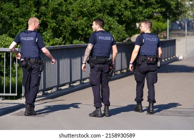 Police patrol of three policemen armed and with bullet proof wests on patrol at Dreirosen Bridge at City of Basel on a sunny spring day. Photo taken May 11th, 2022, Basel, Switzerland.