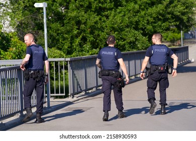 Police patrol of three policemen armed and with bullet proof wests on patrol at Dreirosen Bridge at City of Basel on a sunny spring day. Photo taken May 11th, 2022, Basel, Switzerland.