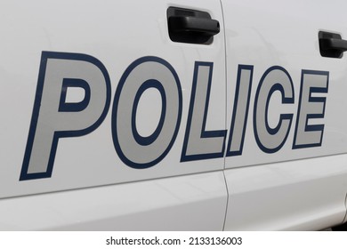 POLICE Printed On The Side Of A Police Car In Bold Silver Text With Blue Outline.