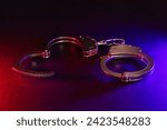 Police raid at night and you are under arrest concept. Silhouette of handcuffs. Image with the flashing red and blue police lights dark background.