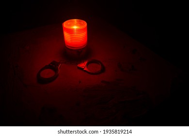 Police Raid At Night And You Are Under Arrest Concept. Silhouette Of Handcuffs With Flashing Red Police Light At Foggy Background. Selective Focus