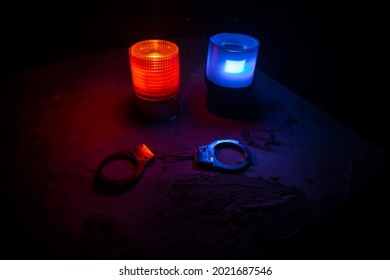 Police Raid At Night And You Are Under Arrest Concept. Silhouette Of Handcuffs With Flashing Red And Blue Police Lights At Foggy Background. Selective Focus