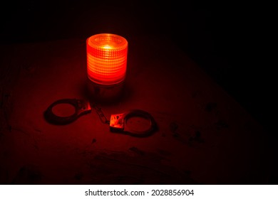 Police Raid At Night And You Are Under Arrest Concept. Silhouette Of Handcuffs With Flashing Red Police Light At Foggy Background. Selective Focus