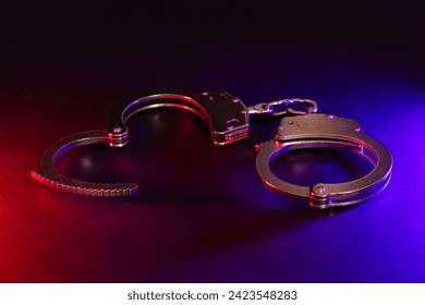 Police raid at night and you are under arrest concept. Silhouette of handcuffs. Image with the flashing red and blue police lights dark background.