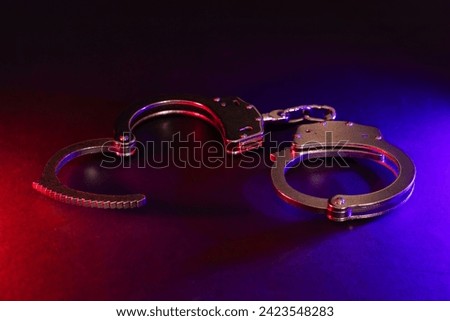 Police raid at night and you are under arrest concept. Silhouette of handcuffs. Image with the flashing red and blue police lights dark background.
