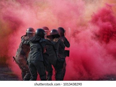  Police In Riot Gear surrounded By Tear Gas And Pink Color Smoke Bomb In Tactical Training