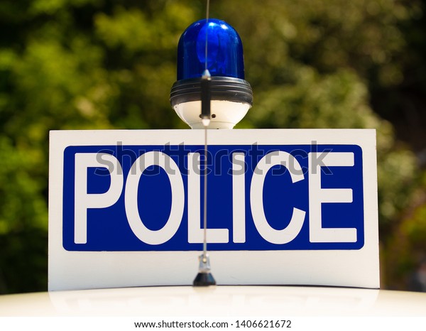 Police sign\
with blue light atop of a patrol\
car.