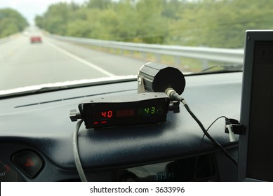 Police speed radar unit in police car driving on 2 lane road.