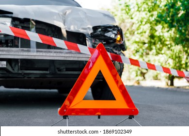 Police Tape And Red Emergency Stop Triangle Sign On Road In Front Of Car Accident. Broken Suv Car In Road Traffic Accident. Car Crash Traffic Accident On City Road After Collision