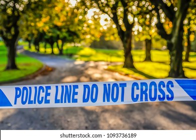 Police Tape Stretched Across The Entrance To A Park Following A Murder