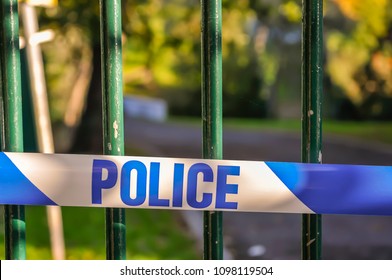 Police Tape Stretched Across The Entrance To A Park Following A Murder