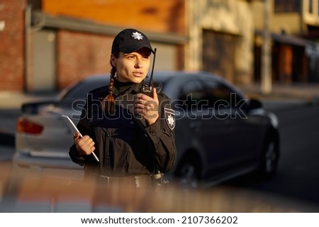 Police woman talking using walkie-talkie during patrolling