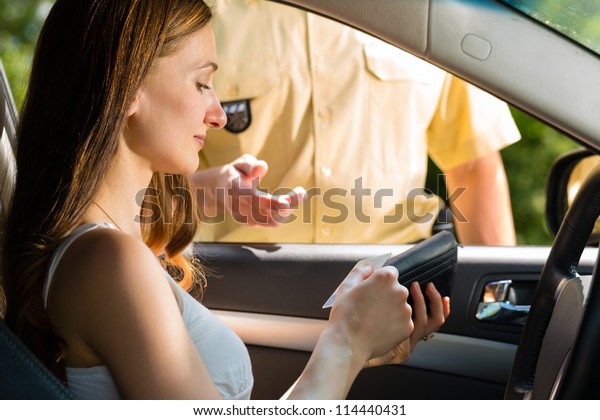 Police - young\
woman with policeman or cop on the street or traffic, she is\
showing her passport or driving\
license