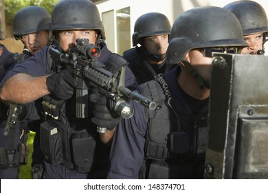 Policeman Aiming While Standing With Coworkers In Training