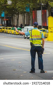 Policeman In Australia, Melbourne Is Controlling Traffic. Back View Of An Australian Traffic Police Stopping Cars With His Hand.