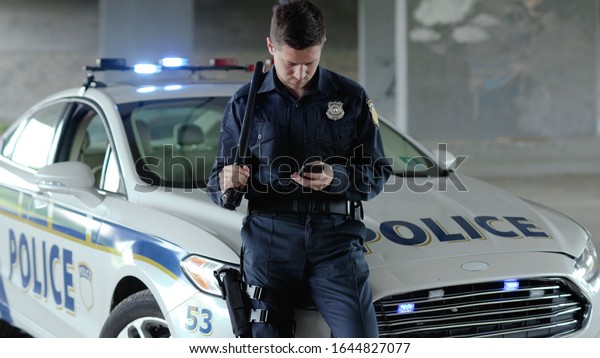Policeman\
cops stand near patrol car use phone accepting emergence call\
enforcement talk officer police uniform auto safety security\
communication control policeman slow\
motion