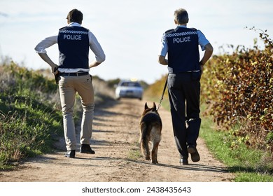 Policeman, dog and walk in field for crime scene or robbery with car for search, safety and law enforcement. Detective, investigation and uniform in outdoor working at countryside with gravel road - Powered by Shutterstock