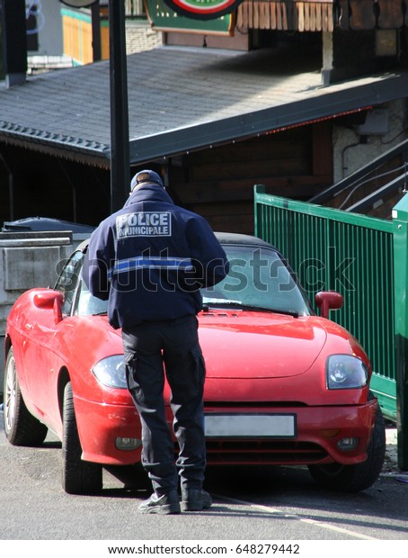 Policeman giving a parking ticket to red\
sports car,Chatel, French\
Alps,France