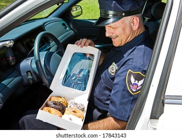 Policeman In His Squad Car, Hungrily Looking At A Box Of Donuts.