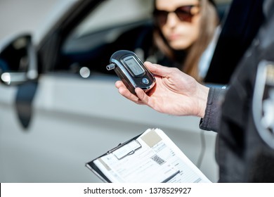 Policeman Holding Device For Checking Alcohol Intoxication While Standing Near The Stopped Car With Woman Driver