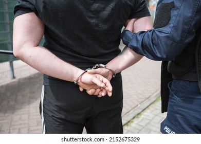 The Policeman Holds The Detained Man In Handcuffs.