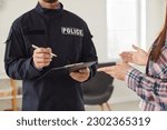 Policeman interrogating woman or witness regarding police investigation. Male police officer in uniform writing down testimonies to investigate burglary. Police investigation concept