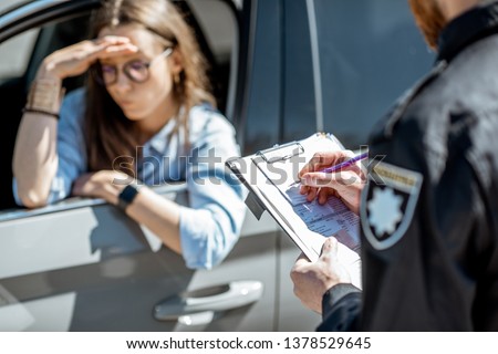Policeman issuing a fine for violating the traffic rules to a young woman driver