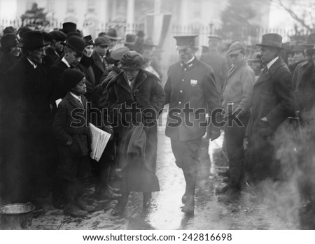 Policeman leads an arrested National Woman's Party protestor away from a woman's suffrage bonfire demonstration at the White House in 1918.