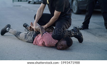 Policeman putting handcuffs on crying black man