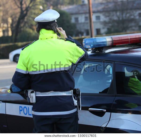 policeman\
talking on the phone near his car in the\
street
