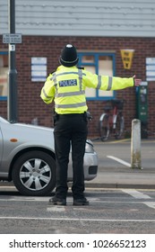 Policeman Wearing Helmet And Hi Vis Reflective Jacket Directs Traffic On Busy Road