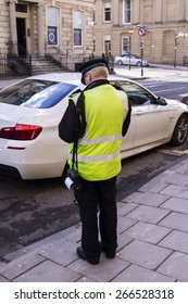 POLICEMAN,SHOT FROM BACK, GIVING A TICKET FOR BAD PARKING OR NOT PAYING TAX ,IN A SUNNY DAY IN STREETS OF UK