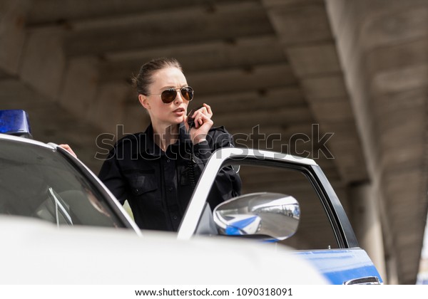 policewoman talking\
by radio set near police\
car
