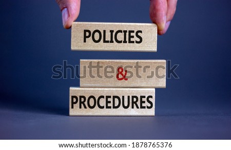 Policies and procedures symbol. Wooden blocks form the words 'Policies and procedures' on grey background. Male hand. Business and policies and procedures concept. Copy space.