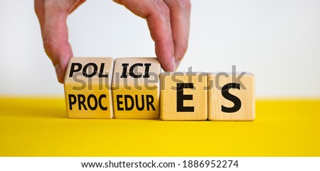 Policies vs procedures symbol. Male hand flips wooden cubes and changes the word 'procedures' to 'policies'. Beautiful yellow table, white background, copy space. Business and policies concept.