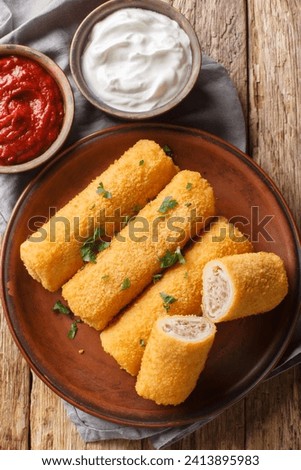 Polish Krokiety Croquettes are pancakes rolled with stuffing, breaded and fried in a pan closeup on the plate on the wooden table. Vertical top view from above
 Zdjęcia stock © 