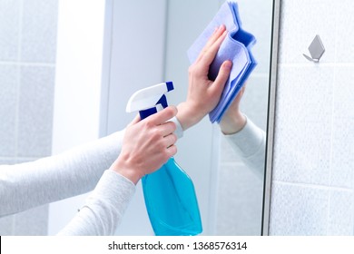 Polish mirror with rag and spray in bathroom at home. Housekeeping and cleaning service. Clean house - Powered by Shutterstock