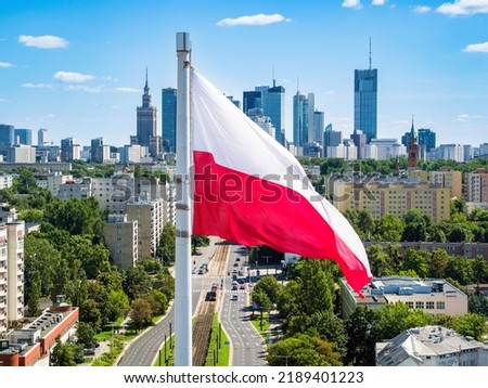 Polish national flag against skyscrapers in Warsaw city center, aerial landscape under blue sky