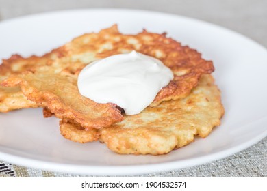 Polish potato pancakes served with sour cream. Polish traditional placki ziemniaczane on white plate.