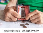 Polish senior woman with work-worn hands pours out small change from her purse. Polish złoty. financial concept. Poland, retiree finances. close up