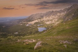 Polish Tatras, Zielony Staw Gasienicowa Valley In Summer At A Pink Sunset, Wild Goats Nibble Grass On A Cliff. High Quality Photo
